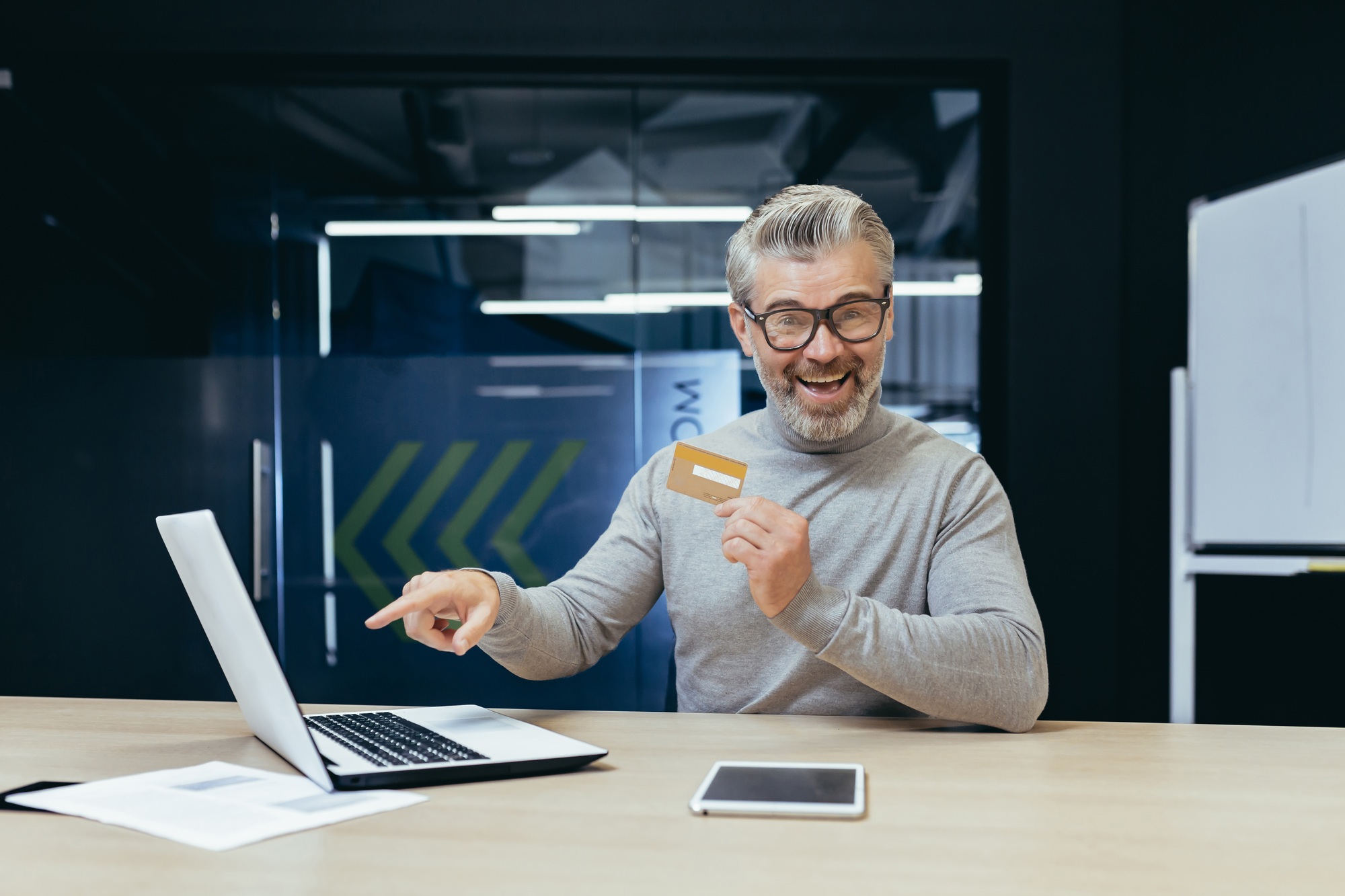 Successful gray haired businessman rejoices and celebrates completion of money transfer transaction